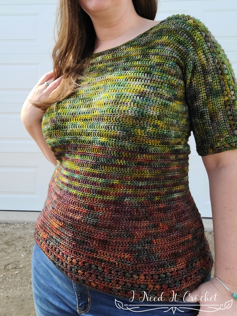 May include: A crochet top with a green, yellow, and brown color scheme. The top has a scoop neck and short sleeves. The bottom of the top has a crocheted border.