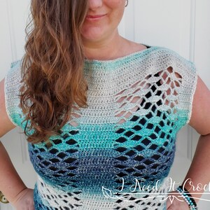 May include: A crocheted top with a light blue, teal and white ombre design. The top has a loose fit and a wide neckline. It features a delicate openwork pattern throughout.