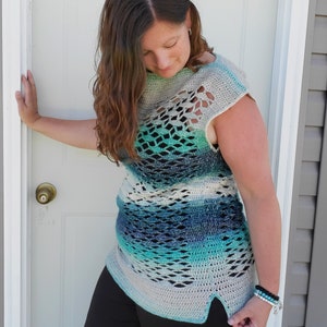 May include: A crocheted top with a blue, green and white ombre pattern. The top has a loose fit and a scoop neck. It features a delicate openwork design and a side slit.