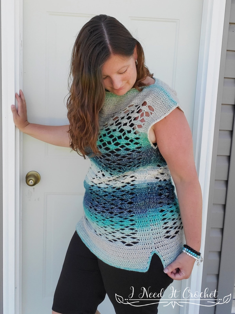 May include: A crocheted top with a blue, green and white ombre pattern. The top has a loose fit and a scoop neck. It features a delicate openwork design and a side slit.