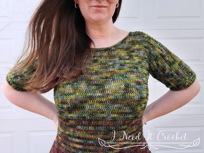 May include: A green, brown, and yellow crochet top with short sleeves. The top has a scoop neck and is made with a variegated yarn.