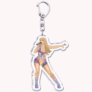 May include: A clear acrylic keyring featuring a stylized illustration of a female singer in a colorful bodysuit and boots, holding a microphone. The keyring has a silver-coloured metal clasp.