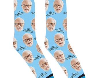 Peut inclure: Une paire de chaussettes bleues avec un motif répété d'un visage d'homme et le texte "#1 GRANDPA".