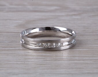 May include: A silver wedding band with a row of small diamonds set in a channel setting.