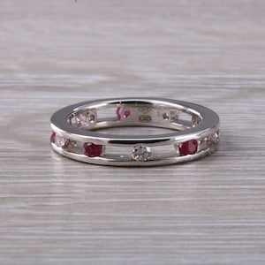 May include: A silver band ring with a double row of small red and white gemstones.