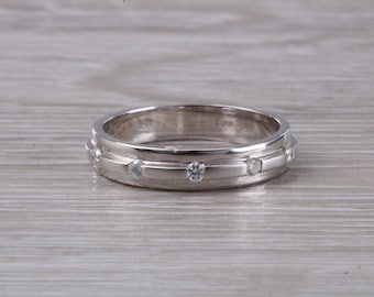 May include: A silver wedding band with a grooved design and five small diamonds set into the band.