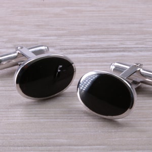 May include: A pair of silver cufflinks with black oval-shaped stones.