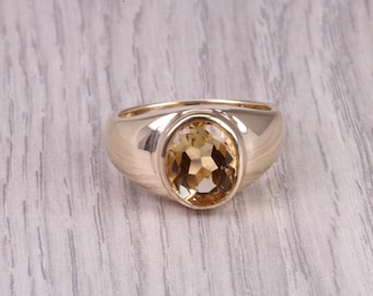 May include: A gold ring with a large oval-shaped topaz gemstone.
