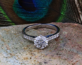 May include: A silver engagement ring with a large, round, clear diamond center stone and smaller diamonds set in a band.