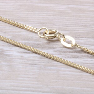 May include: A gold chain necklace with a lobster clasp closure. The chain is a delicate, fine-link style.