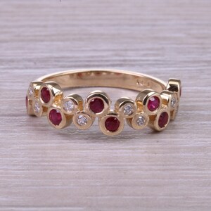 May include: A gold band ring with a cluster of red rubies and white diamonds set in a circular pattern.