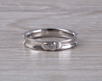 May include: A silver band ring with a small round diamond and two heart-shaped cutouts on either side of the diamond.