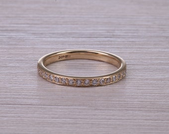 May include: A thin gold band with a row of small diamonds set into the metal. The band is smooth and polished.