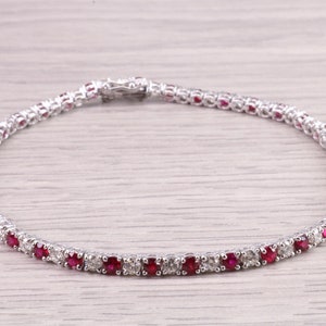 Könnte beinhalten: Ein Tennisarmband aus Weißgold mit abwechselnd roten Rubinen und Diamanten.