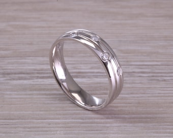 May include: A silver wedding band with a double row of grooves and four small diamonds.