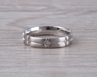 May include: A silver wedding band with a grooved design and three small diamonds.