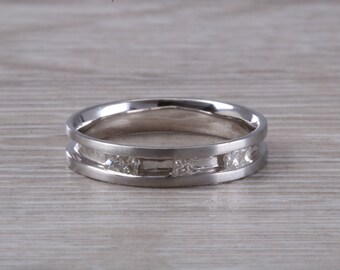 May include: A silver wedding band with a channel setting of small, clear diamonds.