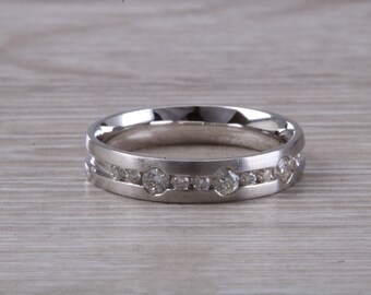 May include: A silver wedding band with a row of small diamonds set in a channel setting.