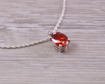 May include: A silver chain necklace with a pendant featuring a large, oval-shaped, orange gemstone surrounded by a silver setting.