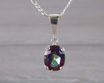 May include: A silver chain necklace with a pendant featuring a large oval-shaped iridescent gemstone. The gemstone has a rainbow of colors, including purple, green, and blue.