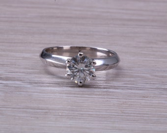 May include: A silver ring with a large, clear, round gemstone set in a six-prong setting.