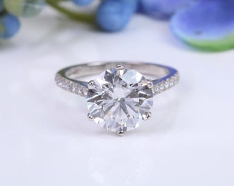 May include: A silver engagement ring with a large, round, clear diamond center stone and a band of smaller diamonds.