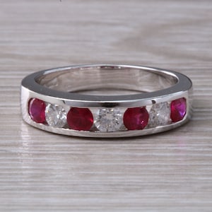 May include: A silver band ring with alternating red rubies and clear diamonds.