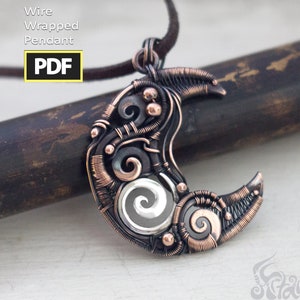 Op de afbeelding: Een halve maan hanger gemaakt van gewikkeld koperdraad met een zilveren spiraalontwerp in het midden. De hanger hangt aan een bruin koord.