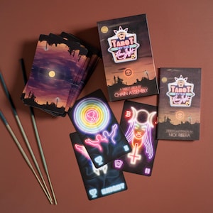 Puede incluir: Una baraja de tarot Tarot by the Neon Light que incluye una caja con un paisaje de atardecer y texto estilo ne&oacute;n. Se muestran varias cartas con ilustraciones de ne&oacute;n vibrantes de figuras, s&iacute;mbolos y copas sobre fondos oscuros, junto a tres varitas de incienso.