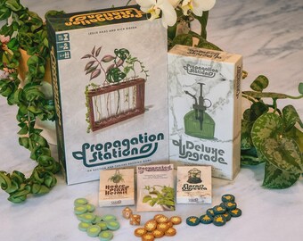 Puede incluir: Un juego de mesa titulado Propagation Station que incluye una caja grande, una caja Deluxe Upgrade, tres mazos de cartas pequeños llamados House Plant Hermit, Unexpected Bloom y Flora Obscura, además de fichas circulares verdes, naranjas y azules.