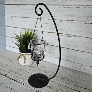 May include: Black metal candle holder with a curved stand and a hanging glass votive with crystal accents.
