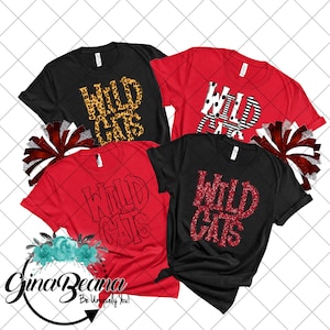 May include: Four t-shirts with the text "Wild Cats" in different styles. The shirts are red and black. One shirt has a leopard print design, one has a black and white striped design, one has a red glitter design, and one has a white outline design.