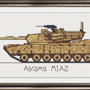 Op de afbeelding: Een kruissteekpatroon van een beige Abrams M1A2 tank met een camouflagepatroon. De tank is naar rechts gericht en heeft het nummer 755 aan de zijkant.