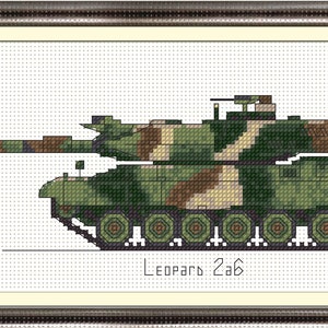 Op de afbeelding: Een groene, bruine en beige camouflage militaire tank met de tekst "Leopard 2A6" eronder gedrukt. De tank is naar rechts gericht en staat op een witte achtergrond.