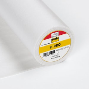 Könnte beinhalten: Eine Rolle weißer Vlieseline H 200, ein  bügelbarer Einlage, ein Stofftyp, der zum Verstärken und Stabilisieren von Stoffen verwendet wird. Das Etikett ist gelb mit schwarzem Text und einem Barcode. Es lautet "Vlieseline H 200 100% PES 90 cm x 25 m".