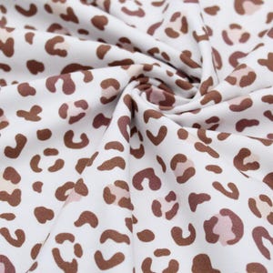 Weicher und elastischer Jersey Stoff mit Leoparden Flecken in braun und rosa auf weißem Hintergrund