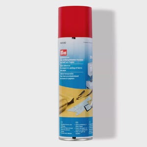 Könnte beinhalten: Eine rot-weiße Sprühkleberdose mit dem Text "Spray adhesive for temporary gluing of fabric and paper". Die Dose ist zylindrisch und enthält Produktinformationen und Markenlogos.