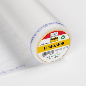 Könnte beinhalten: Rolle weißen Vliesstoffs mit gelb-rotem Etikett. Das Etikett lautet "H 180/308" und enthält Waschanweisungen. Die Rolle ist 90 cm breit und 25 Meter lang.