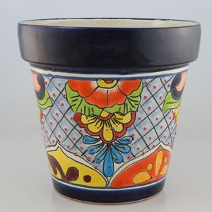 May include: A blue ceramic flower pot with a colorful floral design. The pot features a blue, white, yellow, orange, red, and green floral pattern.