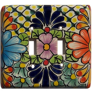 May include: A ceramic light switch cover with a colorful floral design. The design features blue, pink, orange, yellow, and green flowers on a white background.