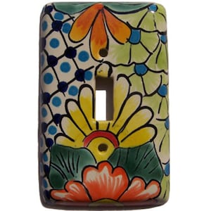 May include: A ceramic light switch cover with a colorful floral design. The design features yellow, orange, red, green, and blue flowers on a white background.