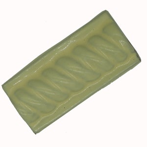 May include: A pale green ceramic tile with a raised, textured design of a repeating wavy pattern.