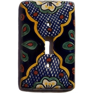 May include: A ceramic light switch cover with a colorful Mexican Talavera design. The cover features blue, yellow, green, white, and red colors in a floral pattern.