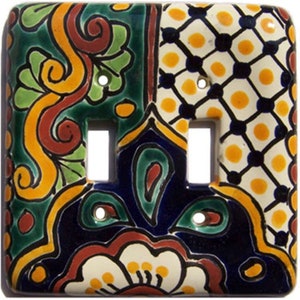 May include: A double light switch cover with a colorful Mexican Talavera design. The cover features a blue, green, yellow, and white floral pattern with geometric accents.