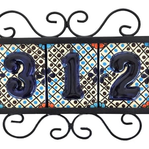 May include: A black metal frame with scrolled details holds three blue ceramic tiles with the numbers 312 on a white background with black and blue geometric patterns.