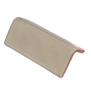May include: A white ceramic corner tile with a slightly textured surface. The tile has a slightly rounded edge and a beveled corner.