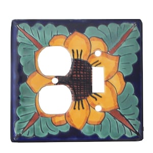 May include: A decorative ceramic light switch cover with a sunflower design. The cover features a vibrant yellow sunflower with a dark center, surrounded by green leaves and a dark blue border. It has two outlet holes and a switch opening.