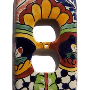 May include: Rectangular ceramic double outlet cover with a vibrant floral design. The cover features a cream-colored base with colorful accents of yellow, orange, red, green, and blue. The design includes stylized flowers and geometric patterns.