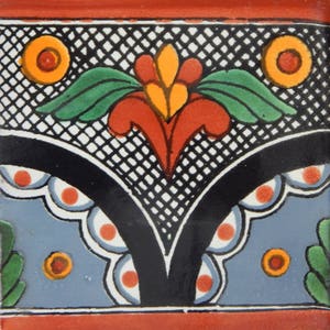 May include: A colorful ceramic tile with a black and white grid pattern, a red and yellow floral design, and white and red dots around the edges.