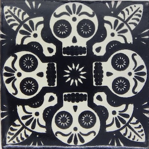 May include: Black and white tile with a repeating pattern of four stylized skulls with floral accents. The skulls have two eye sockets and a nose, and are outlined in black.